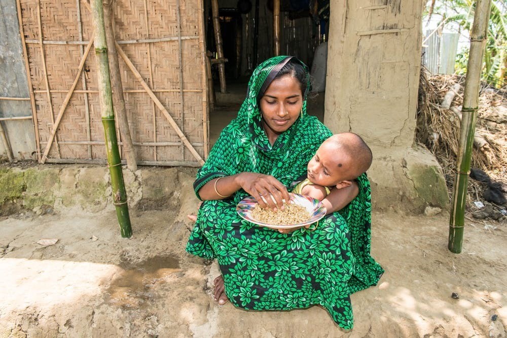 Một phụ nữ ở Bangladesh cho con mình ăn gạo bổ sung bột cá bổ dưỡng.